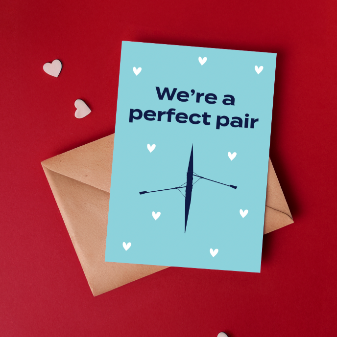 light blue card with navy text which reads we're a perfect pair. navy rowing boat graphic and white hearts.